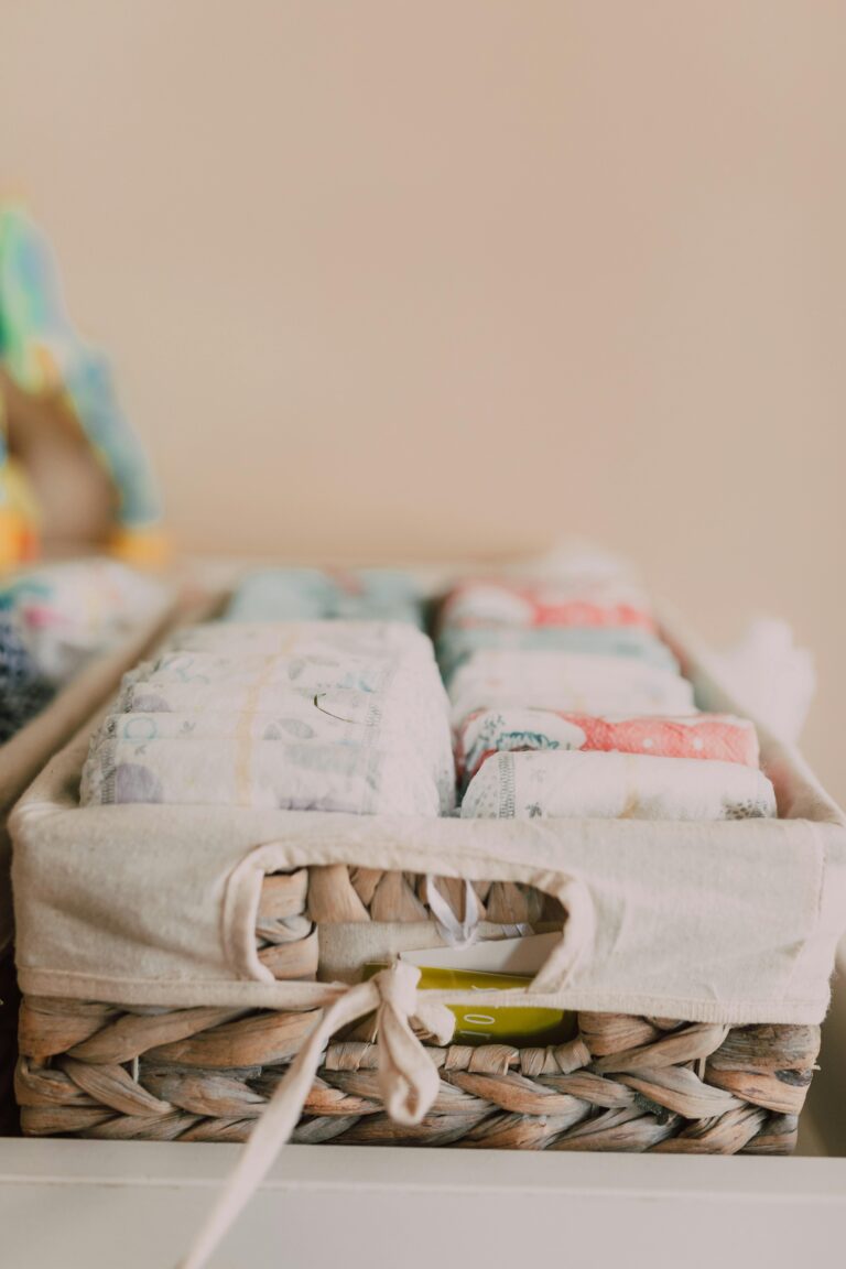 Close-up of a woven basket with neatly arranged baby diapers in a neutral-toned nursery.