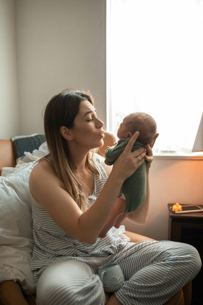 A tender moment of a mother holding her newborn baby by a bright window indoors.